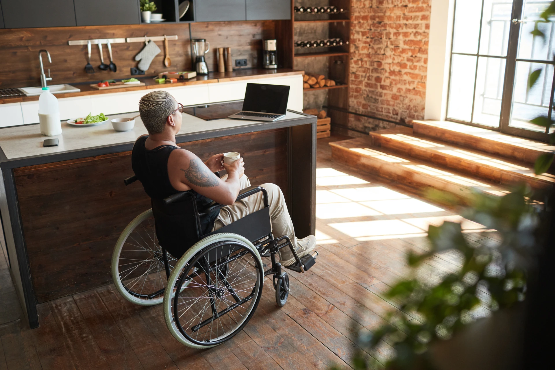 wheelchair bound person sitting in their kitchen enjoying a coffee