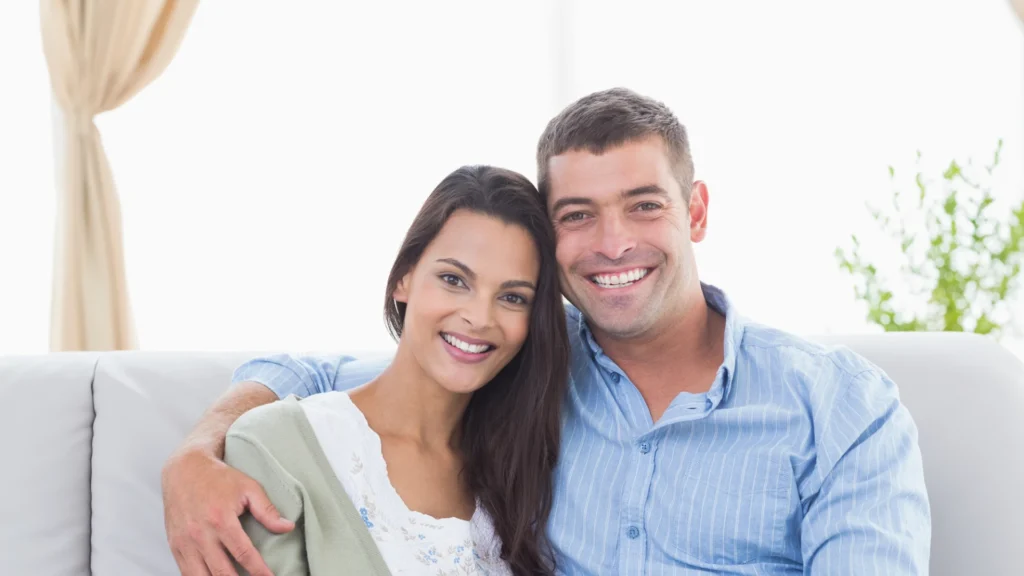 a man and woman sitting on a couch smiling